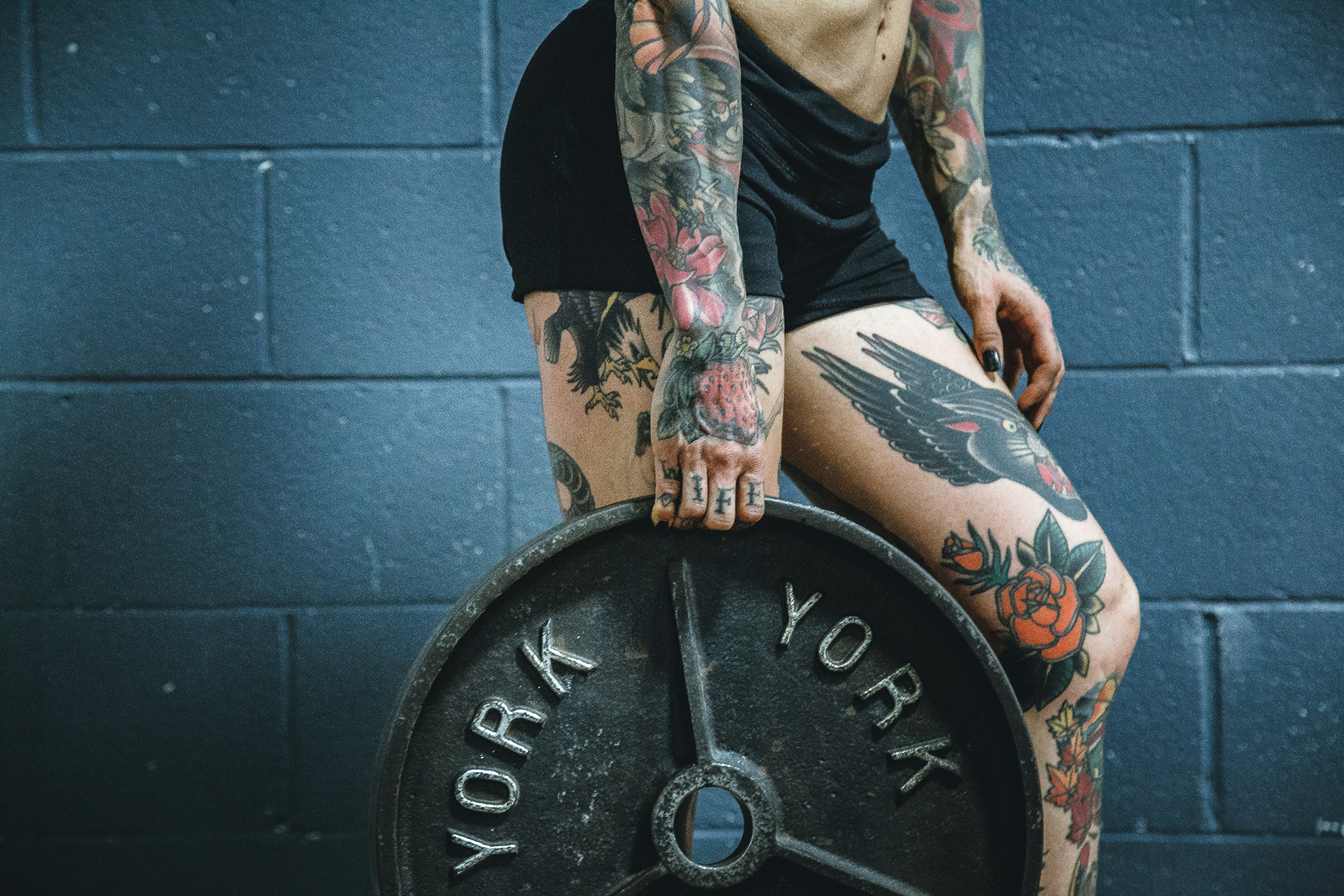 mulher tatuada segurando anilha
